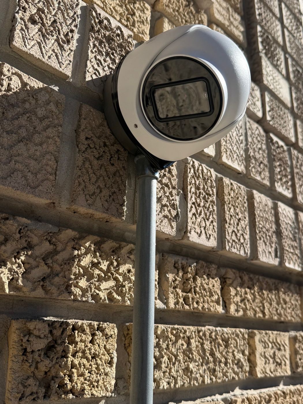 Exterior security camera mounted on a stone building wall